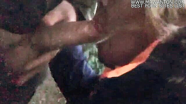 A mature blonde woman kneels outdoors, giving a big cock a handjob and blowjob, culminating in a cumshot in her mouth. Reality action with European MILF.