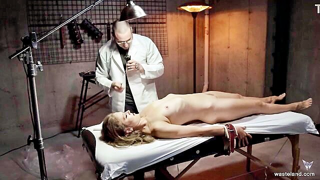 gorgeous blonde bound with wrist cuffs to table by loving master in bondage play : Wasteland